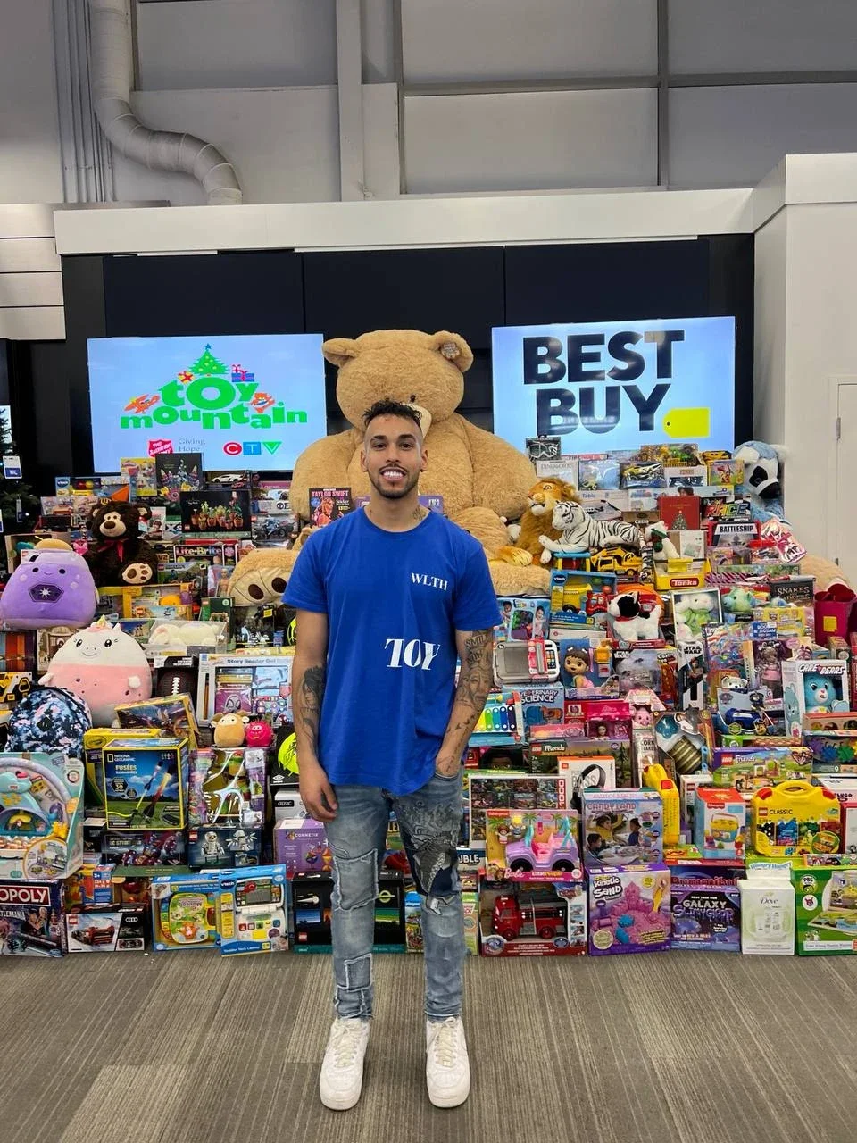 Marcus Nandlal of WLTH in front of the Toy Mountain donations at Best Buy